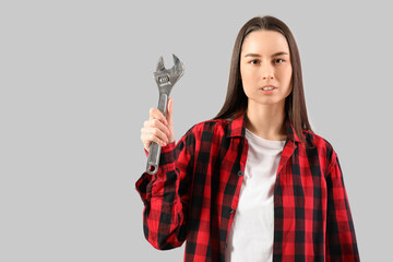 Young woman with adjustable wrench on grey background. Women history month