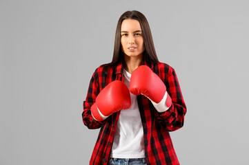 Beautiful young woman in boxing gloves on grey background. Women history month