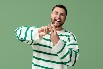 Handsome young man making hashtag sign with fingers on green background