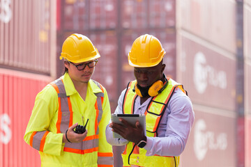 Group of diverse male container yard worker working and checking container boxes at commercial dock site. Black male and Asian male people worker inspecting container boxes from cargo freight ship