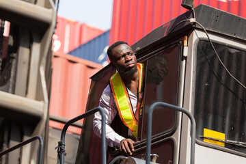 African American male container yard worker working, control container boxes on forklift truck before loading at commercial dock site. Black male people worker work at cargo freight ship - obrazy, fototapety, plakaty