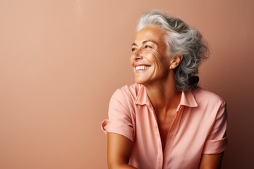 Portrait of a smiling senior woman on a beige background.