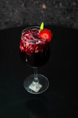 Copa de clericot con frutos rojos y fresa con menta en un fondo negro 