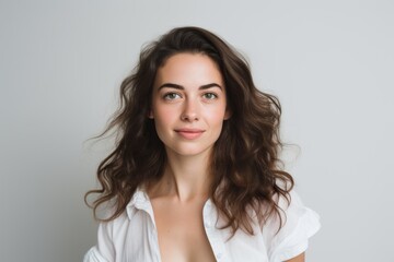 Portrait of a beautiful young woman with long curly hair in a white shirt.
