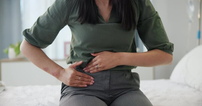 Pain, period and woman hands with stomach ache, endometriosis or PCOS health problem on a bed. Abdomen, appendicitis or digestion issue of a female person with uncomfortable cramps in a hospital