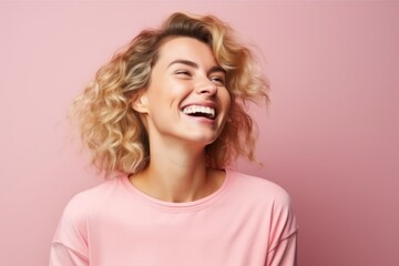 Portrait of a happy young woman laughing and looking up over pink background