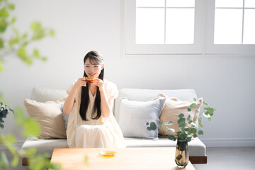 Asian (Japanese) woman with long hair relaxing in room Drinking tea Wide-angle copy space available