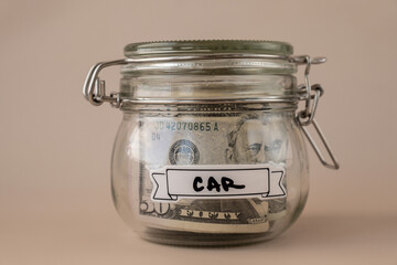 Glass jar full of American currency dollars cash banknote with text CAR. Preparation saving money. Moderate consumption and economy