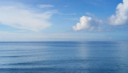 Obraz premium Tranquil Seascape under a Clear Blue Sky with Fluffy Clouds on a Sunny Summer Day