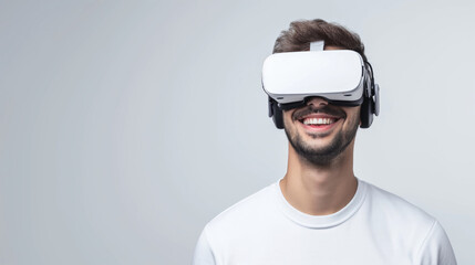 Portrait of young man wearing virtual reality glasses over white background with copy space. Smiling man in white VR goggles. - obrazy, fototapety, plakaty