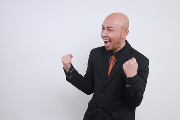 Happy Asian bald man in suits clenched fist showing victory gesture or celebrating successful business agreement