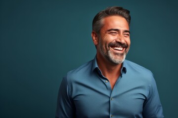 Portrait of a handsome middle-aged man laughing over blue background.