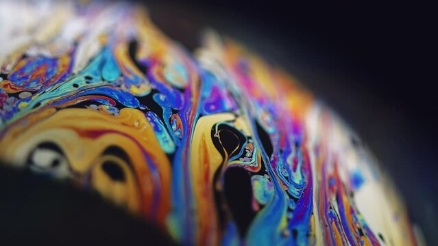 Paint blend. Holographic sphere. Defocused blue orange color stain bubble oil fluid ink mix wave motion marble texture on dark black abstract art background.