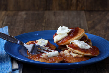 Fork cutting into messy plateful of pikelets pancakes battercakes illustrating overindulgent eating...