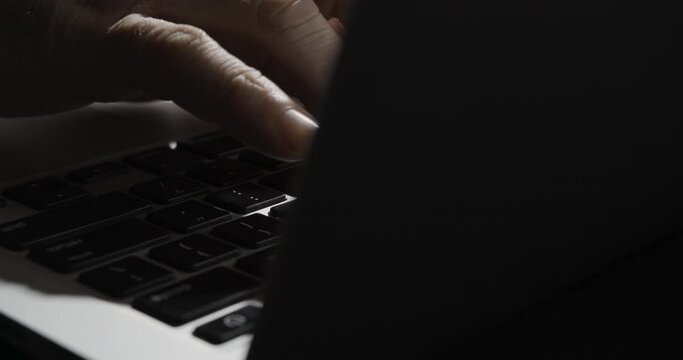 Fingers Typing on Laptop Keyboard from Behind Monitor
