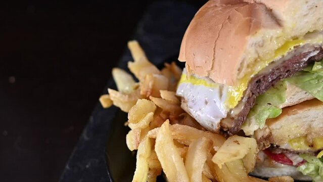 slow motion video of a close-up of a breaded lomito or goat sandwich reinforced with beef lettuce tomato mayonnaise mustard between breads eggs accompanied with French fries