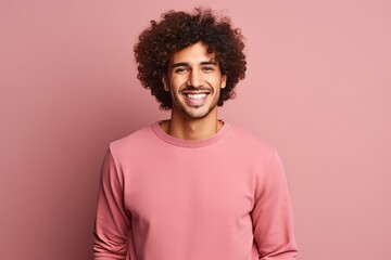 Fototapeta na wymiar Portrait of a happy young latin man smiling against pink background