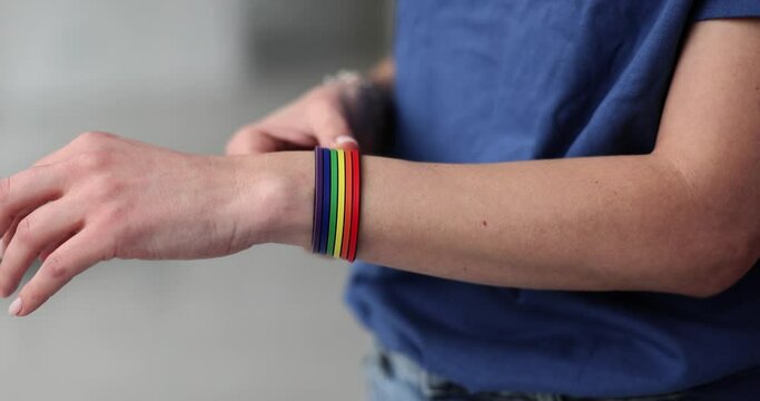 Closeup of hand putting on a bracelet with colors of LGBT flag