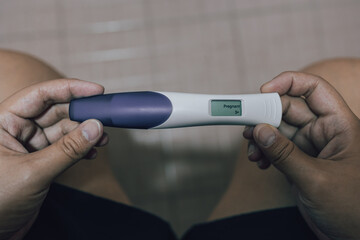 A close-up image of a woman's hands tenderly cradling a positive home pregnancy test - obrazy, fototapety, plakaty