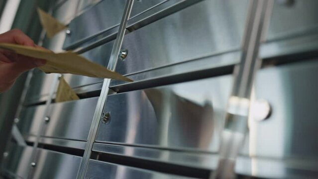 Mailman hand put letters into silver containers closeup. Worker delivering post