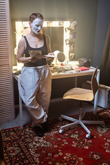 Vertical full length portrait of young woman as mime artist rehearsing backstage in theater...
