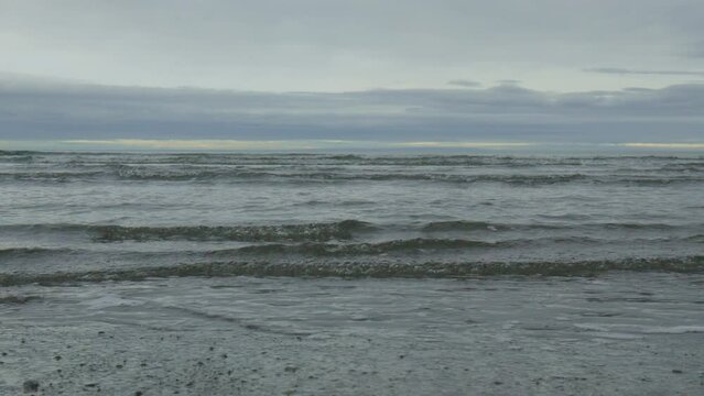 Ocean sea shore waves in slow motion muddy cloudy gray sky horizon line