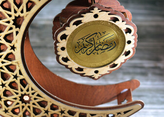 Translation of Arabic text (Ramadan Kareem or Happy generous Ramadan) on a round wood piece...