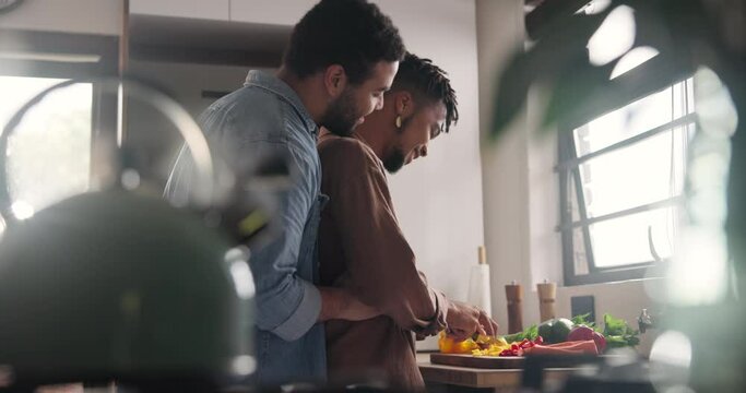 Gay couple, cooking food and kiss in kitchen, love and bonding together. Lgbtq men, romance and embrace in home, cutting vegetables or smile in preparation for organic healthy salad on valentines day