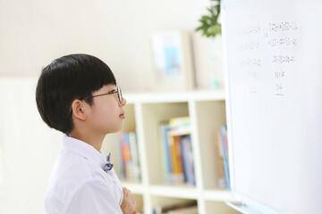 A smart and cute student who thinks and ponders carefully while solving math problems in front of the blackboard.
