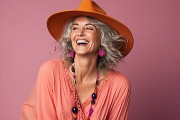 Portrait of a beautiful happy woman in orange hat on pink background