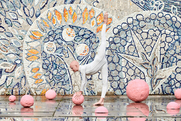 Outdoor dance of young ballerina girl with alopecia in white futuristic suit with plastic and flexible movements among pink spheres on abstract mosaic Soviet background, symbolizes self expression