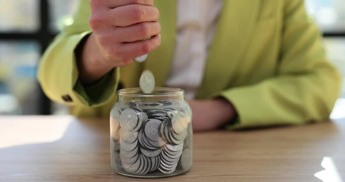 Female hands pour handful of coins into jar