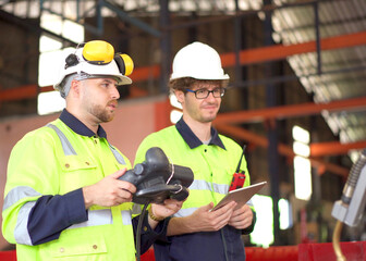 Mechanical or robotic software engineers working together on a robotic arm in modern manufacturing factory. 