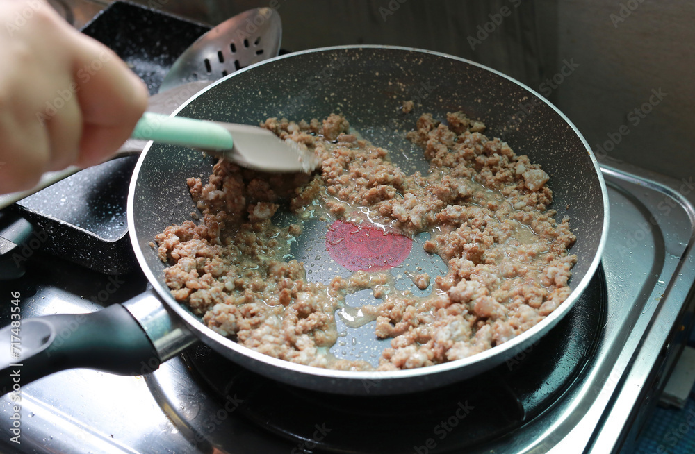 Wall mural people hand stir-fried minced pork in a pan.