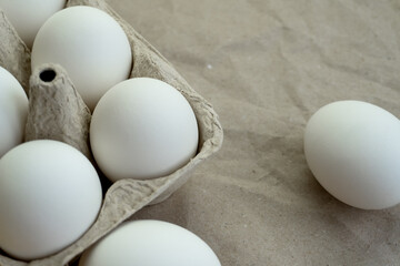 White chicken eggs in a box lie on the table.