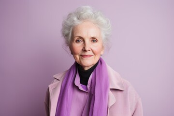 Portrait of a beautiful senior woman in a coat on a purple background