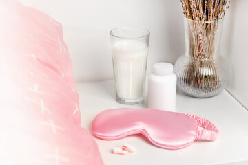 Bedside table with a silk sleep mask, earplugs and lavender and warm milk for a good night's sleep...