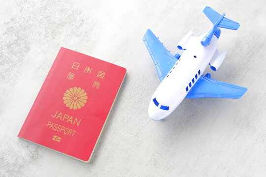 日本のパスポート（一般旅券10年用赤色）と飛行機のおもちゃで、海外旅行のイメージ
