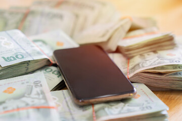 Cropped image of Thai bank notes and mobile phones placed on a brown wooden table.