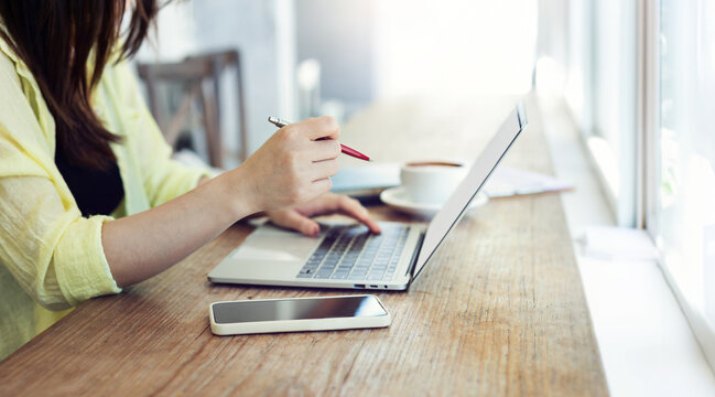 Young Asian Woman Using Computer Laptop And Smart Phone Working In A Cafe And Drinking Coffee, Young Asian Girl Student With Computer Study Online In The Summer