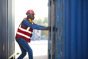 African factory worker or foreman opening the container door in warehouse storage