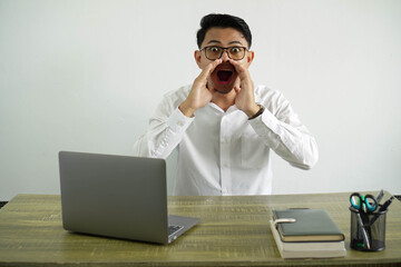 young asian businessman in a workplace shouting and announcing something, wear white shirt with...