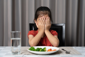 Little cute kid girl refusing to eat healthy vegetables. Children do not like to eat vegetables.
