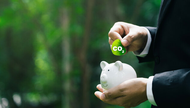 Carbon credit concept with businessman holding leaf green globe reducing saving carbon emissions carbon neutral concept.