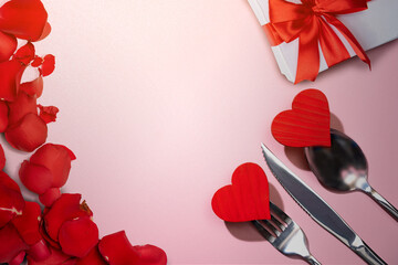 Silverware of fork, knife, and spoon with a red heart and gift box and rose petal