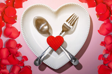 Heart plate with silverware of spoon and fork with a red heart and rose petal