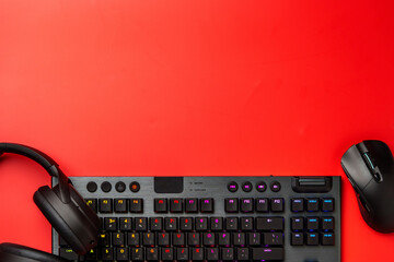 Computer keyboard and headphones on red background top view