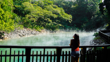 Obraz premium Hot spring water at Beitou Thermal Valley or Geothermal Valley, Taiwan. Woman traveler looking at Hot spring pond at Xinbeitou thermal valley in Taiwan.