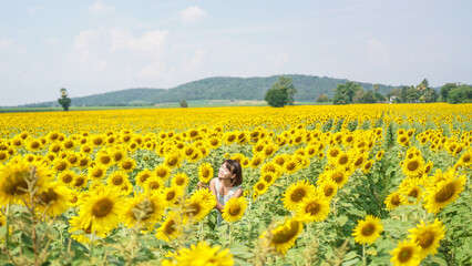 Smile face and short hair asian woman in the field of sunflowers, standing arm raised. Portrait of a beautiful asian woman feeling happy and funny in the sunflower field.