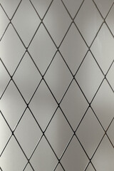 Diamond-shaped lattice made of thin metal on glass. Geometric background